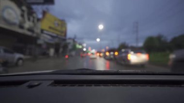 Yağmurlu bir günde, güzel ışıklar ve bokeh ile gece sokaklarda dolaşan bir arabanın içinden çekilmiş bir video..