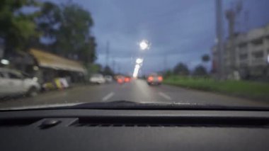 Yağmurlu bir günde, güzel ışıklar ve bokeh ile gece sokaklarda dolaşan bir arabanın içinden çekilmiş bir video..