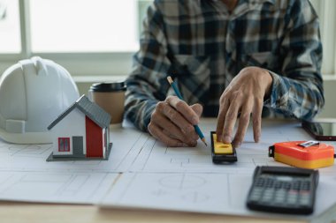 Ev tasarımcısı Persson Mühendis için ev geliştirme belgeleriyle çalışan mimar iç mimari tasarımcı - El, mimari ekipmanlarla baskı üzerine planlar çizdi. Mimarlar masada sohbet ediyorlar.