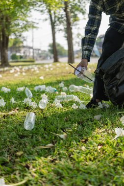 Elleri plastik şişelerle kapalı olan gönüllüler, ekolojik arka plandaki çöp torbalarına plastik şişeler, orman temizleme konsepti ve çevre ilkeleri topladı.