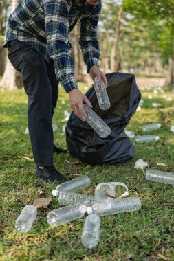Elleri plastik şişelerle kapalı olan gönüllüler, ekolojik arka plandaki çöp torbalarına plastik şişeler, orman temizleme konsepti ve çevre ilkeleri topladı.