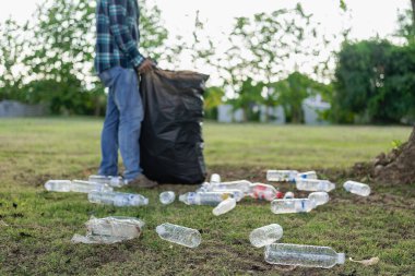 Elleri plastik şişelerle kapalı olan gönüllüler, ekolojik arka plandaki çöp torbalarına plastik şişeler, orman temizleme konsepti ve çevre ilkeleri topladı.