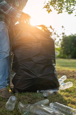 Elleri plastik şişelerle kapalı olan gönüllüler, ekolojik arka plandaki çöp torbalarına plastik şişeler, orman temizleme konsepti ve çevre ilkeleri topladı.