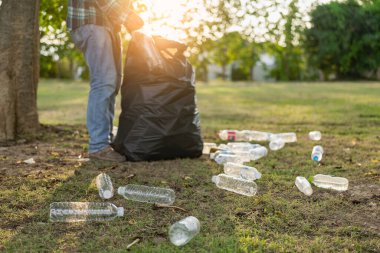 Elleri plastik şişelerle kapalı olan gönüllüler, ekolojik arka plandaki çöp torbalarına plastik şişeler, orman temizleme konsepti ve çevre ilkeleri topladı.