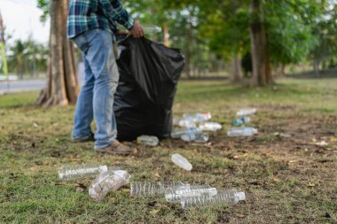 Elleri plastik şişelerle kapalı olan gönüllüler, ekolojik arka plandaki çöp torbalarına plastik şişeler, orman temizleme konsepti ve çevre ilkeleri topladı.