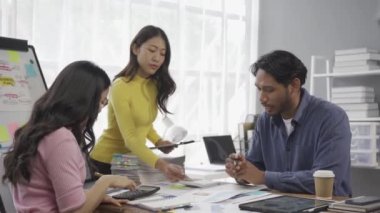 İş planlarıyla ilgili bir toplantıda çalışan bir grup Asyalı işadamı iş konferansı odasında finansal belgeleri paylaşan insanlarla birlikte dizüstü bilgisayarlardan finansal çizelgeleri sunup açıkladılar..