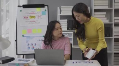 Yeni bir proje üzerinde birlikte çalışan iki Asyalı iş arkadaşı, finans hakkında konuşan iş kadınları, piyasa, ekonomi ve bankaların modellerine bakıyor.