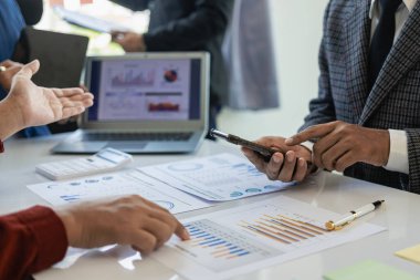 Bir kahve dükkanında yeni bir projenin beyin fırtınası yapan bir şirketin finansal bilgilerine ve finansal belgelerine sahip bir dizüstü bilgisayarın önünde oturan bir iş ekibinin yakın çekimi..