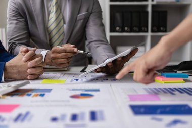 Bir kahve dükkanında yeni bir projenin beyin fırtınası yapan bir şirketin finansal bilgilerine ve finansal belgelerine sahip bir dizüstü bilgisayarın önünde oturan bir iş ekibinin yakın çekimi..