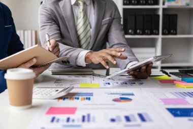 Bir kahve dükkanında yeni bir projenin beyin fırtınası yapan bir şirketin finansal bilgilerine ve finansal belgelerine sahip bir dizüstü bilgisayarın önünde oturan bir iş ekibinin yakın çekimi..