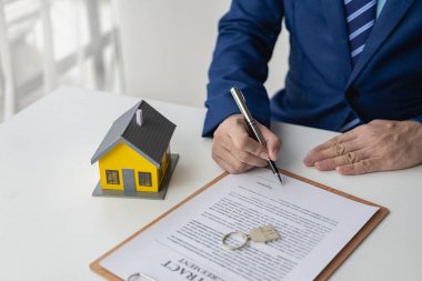 Ev satışları danışmanı ve sigortacısı, emlakçı sözleşmeli belgeler ve bilgisayarla çalışıyor.