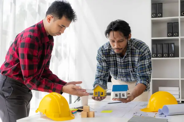 Architects discuss architectural plans for building a house. The agent sets the price of the property for sale. Valuation of assets in construction projects