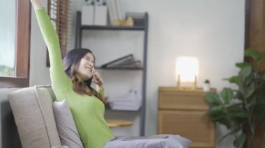 Rahat genç Asyalı kadın evdeki rahat bir kanepede dinleniyor. Sakin ol, rahatla ve evde temiz hava al. Denge ve sükunet kavramı..