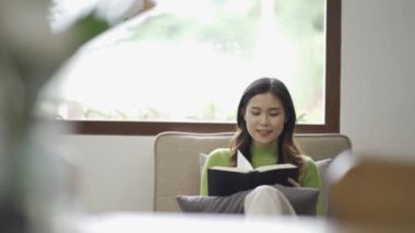 Rahat genç Asyalı kadın evdeki rahat bir kanepede dinleniyor. Sakin ol, rahatla ve evde temiz hava al. Denge ve sükunet kavramı..