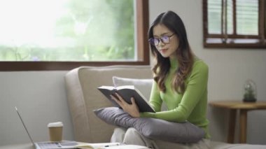 Rahat genç Asyalı kadın evdeki rahat bir kanepede dinleniyor. Sakin ol, rahatla ve evde temiz hava al. Denge ve sükunet kavramı..