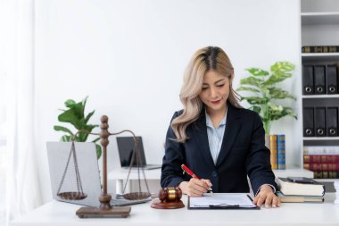Ofiste ya da mahkemede çalışan genç bayan avukat Asya 'nın başarılı kadınının kontratını ve adalet terazisini çekiçle kontrol et. hukuki danışma kavramı