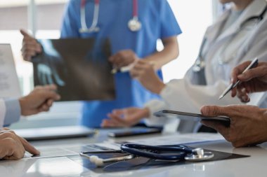 Beyaz önlüklü ve ameliyat önlüklü doktorla görüşüp hasta kayıtlarını tartışıyorlar. Dijital tablet üzerinde çalışan doktorlar, bilgisayar kullanan doktorlar tablet teknolojisi.