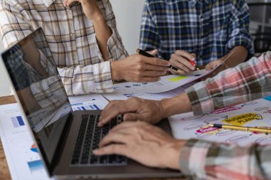 Genç iş adamlarının iş stratejilerini analiz etmek ve planlamak için dizüstü bilgisayar ve finansal rapor belgeleriyle beyin fırtınaları. Resmi kapat.