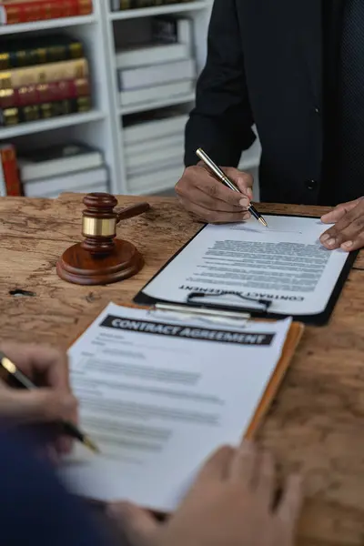 Lawyer discussing contract documents sitting at table in office, legal concept, advice, legal consulting service and scales with judge\'s gavel Vertical close-up photo