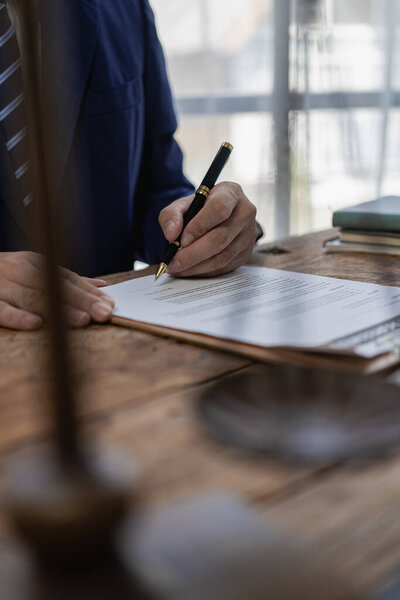 Lawyer discussing contract documents sitting at table in office, legal concept, advice, legal consulting service and scales with judge's gavel Vertical close-up photo