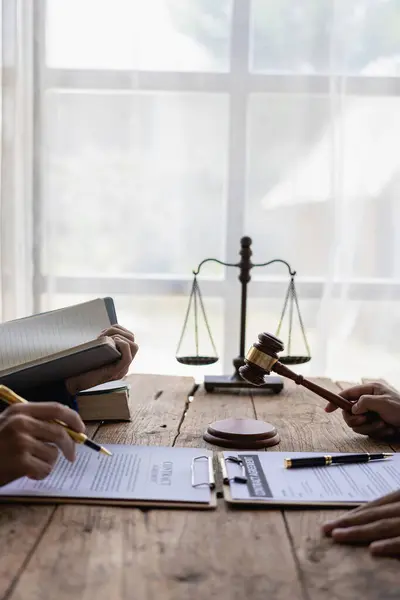Lawyer discussing contract documents sitting at table in office, legal concept, advice, legal consulting service and scales with judge\'s gavel Vertical close-up photo
