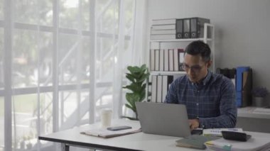 Belgeler, mali grafikler, iş hesapları, tasarruflar, finans ve dünya ekonomisinin analizi için kağıt ve hesap makinesi ile çalışan ciddi Asyalı işadamı.