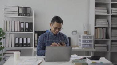 Resmi takım elbiseli mutlu bir iş adamı bir müşteri ya da arkadaşla konuşuyor. Modern bir ofiste otururken bir meslektaşımla akıllı telefondan konuşuyorum..
