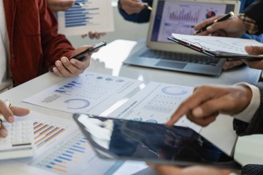 İş adamı veya muhasebe ekibi, istatistiksel raporlar hazırlamak ve pazar verilerini analiz etmek için mali verileri tartışmak üzere grafik veri tablosunu ve dizüstü bilgisayarını analiz ediyor. Resmi kapat.