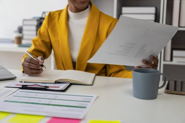 Vergileri hesaplamak ve ofiste online danışmanlık yapmak için yıllık raporla çalışan genç ve güzel Afrikalı bir muhasebeci, dizüstü bilgisayarla online danışmanlık konsepti, video konferansı,