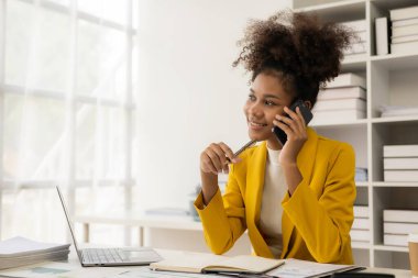 Vergileri hesaplamak ve ofiste online danışmanlık yapmak için yıllık raporla çalışan genç ve güzel Afrikalı bir muhasebeci, dizüstü bilgisayarla online danışmanlık konsepti, video konferansı,