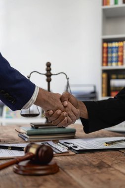 Bir avukat, bir iş ortağının zimmetine para geçirme davasında tanıklık etmeye gelen bir müşteriyle el sıkışıyor. Hukuk danışmanı, sözleşmeler ve davalar uzmanı.