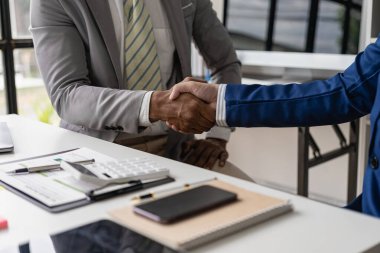 Ofisteki bir toplantıda el sıkışan kendine güvenen iki işadamı ofis brifinglerinde veya müzakerelerde anlaşma yapıyor. Mutlu erkek iş ortakları el sıkışıyor.