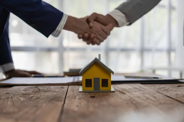 Real estate agent shakes hands with client after the contract is finalized after home insurance and investment loans. Agent and client shake hands after signing the contract to buy a home.