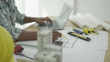 Site yöneticisi, ağır endüstriyel bir inşaat sahasında bir plan üzerinde yaratılan bir projenin taslağını gösteren bir mimar çiziyor..