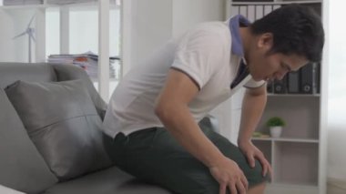 Basurlu genç bir adam oturamaz. Sağlıksız bir adam hasta, basur ağrısı çekiyor, kanepede oturuyor, acı çekiyor.