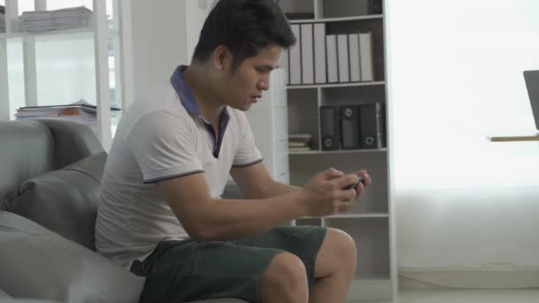 Glad Ung Asiatisk Man Som Använder Mobiltelefon Medan Sitter Soffan — Stockvideo