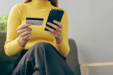 Kadının elinde kredi kartı, akıllı telefon ve dizüstü bilgisayarla elini kapat. Genç bir kadın internet üzerinden ödeme yapıyor. İnternet mağazasından sipariş bilgilerini giriyor, online isim kavramını kullanıyor.