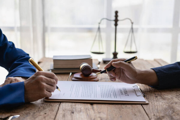 Юристы обсуждают контракты или деловые сделки в юридической фирме. Концепция службы правосудия Крупный план молотка и шкалы сидя рядом друг с другом.