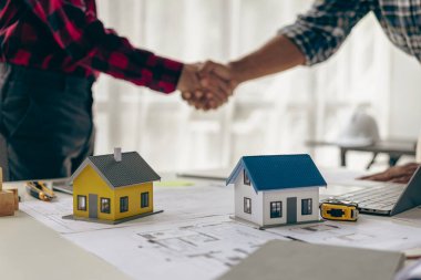 İnşaat işçileri birbirlerini tokalaşarak selamlıyorlar. Koruyucu kasklı ve yelekli inşaat işçileri el sıkışıyor. İş, inşaat, takım çalışması, insanların jestleri ve kavramları.