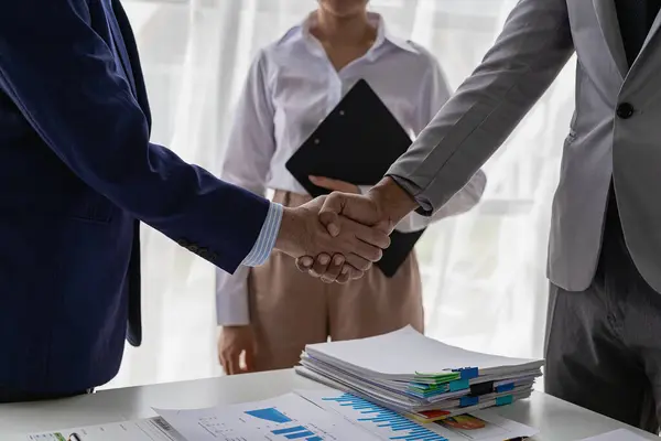 Two businessmen are agreeing on business together and shaking hands after successful negotiations. Shaking hands is a way of greeting or expressing congratulations. Close-up pictures