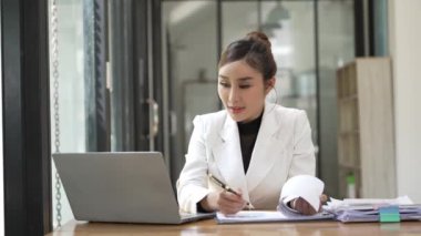 Pazarlama uzmanı, akıllı Asyalı iş kadını iş ofisinde dizüstü bilgisayar ve finansal belgeler üzerinde çalışıyor, proje yöneticisi, iş konsepti, para, 4K