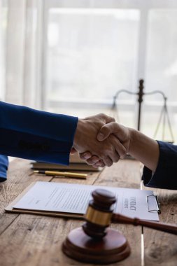 İş adamı avukatla anlaşma yapmak için el sıkışıyor. Mahkeme davaları, hukuki kavramlar, tavsiyeler ve adalet için işe alma şartlarını tartışıyorlar..