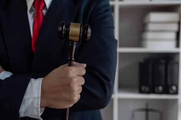 Male hand knocking on wooden judge, law and auction concept Legal concept, lawyer holds hammer and writes contracts and business agreements in law office.