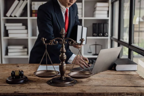 Asian male lawyer working in office with laptop and scales, judge hammer, legal consultant concept.