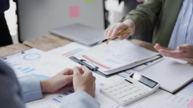 İşadamlarının erkek ve kadın elleri şirketteki projeler için stratejiler planlıyorlar. Çalışma ekibi masada oturup mali grafikleri ve masadaki belgeleri kontrol ediyor.