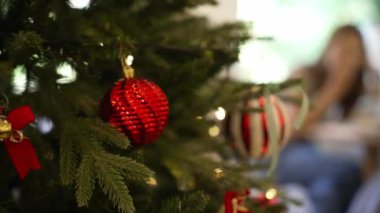 Noel ağacı süslemesi, pürüzsüz hareket eden kamera. Noel ağacında kırmızı toplar ve çelenkler parıldıyor..