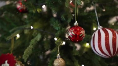 Noel ağacı süslemesi, pürüzsüz hareket eden kamera. Noel ağacında kırmızı toplar ve çelenkler parıldıyor..