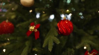 Noel ağacı süslemesi, pürüzsüz hareket eden kamera. Noel ağacında kırmızı toplar ve çelenkler parıldıyor..