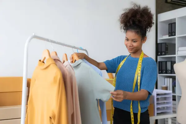 Young African woman selling clothes in streaming video Start a small SME using your smartphone or tablet to receive name orders and ready to ship packages.