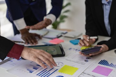 Profesyonel iş ortakları proje planlaması ve sunumunu mali ve yatırım kavramlarını analiz ederek bir beyin fırtınası oturumunda tartıştılar. Yakın plan resimler.